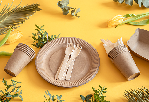 Eco-friendly, stylish recyclable paper tableware. Paper food boxes, plates, and cornstarch Cutlery on a trending orange background.